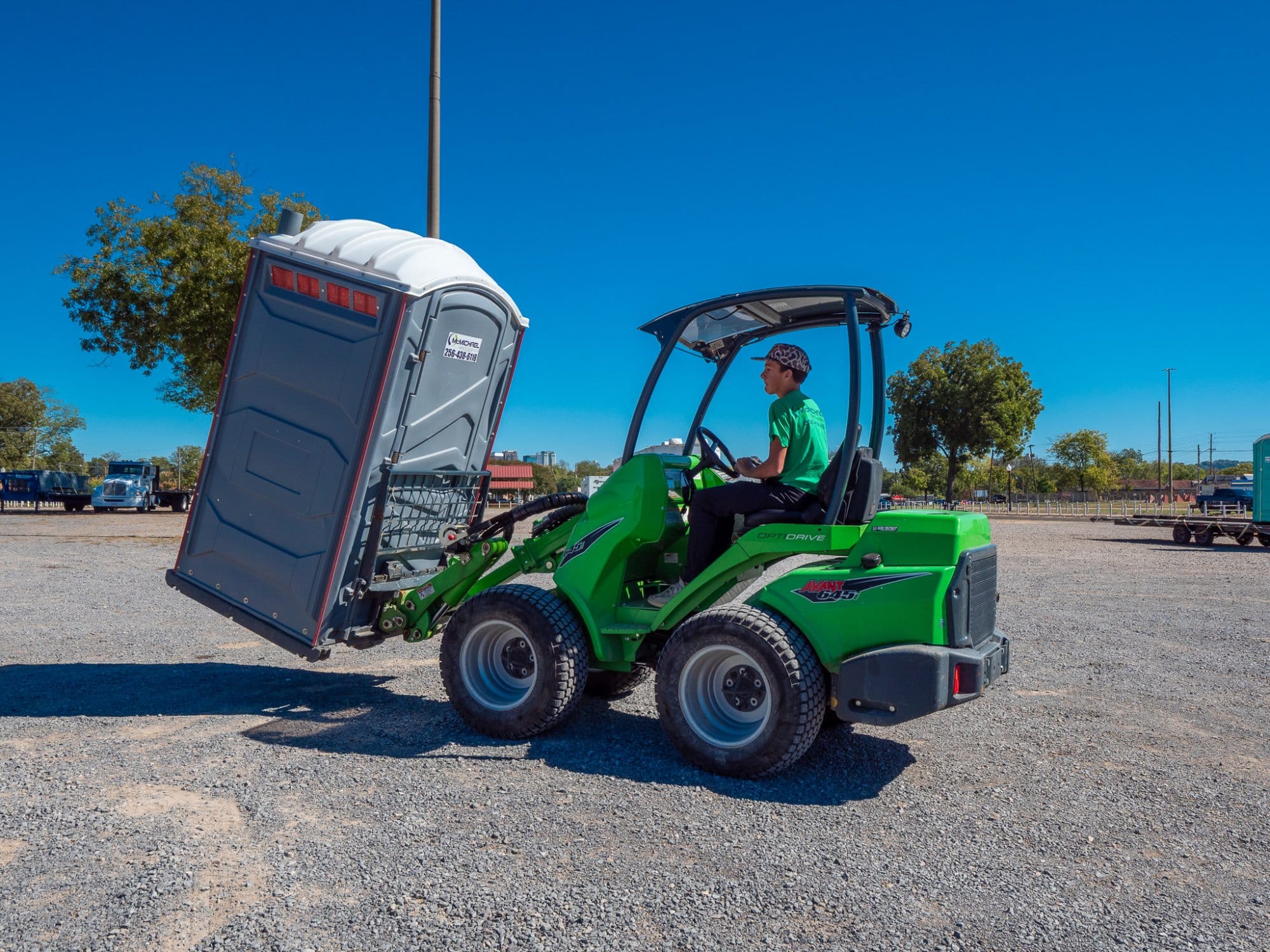 McMichael Waste Services loader moving a portable toilet in the equipment yard