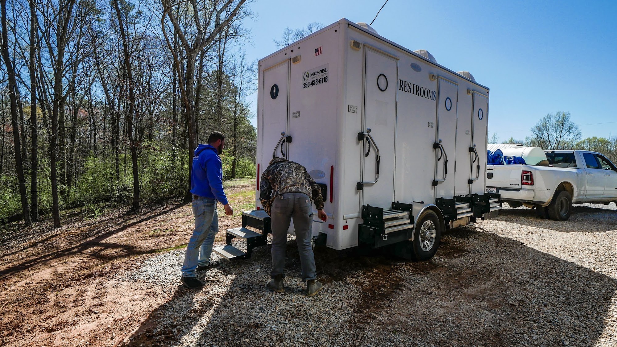 McMichael crew setting up a restroom trailer on a gravel job site